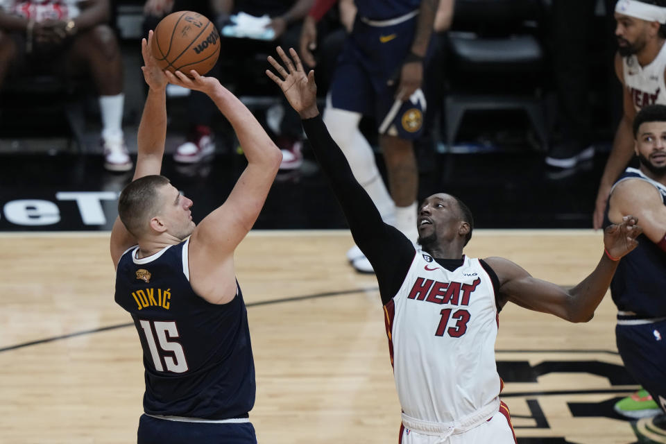Denver Nuggets' Nikola Jokic (15) takes a three-point shot at Miami Heat center Bam Adebayo (13) on defense during the second half of Game 4 of the NBA Finals, Friday, June 9, 2023, in Miami.  (AP Photo/Lynne Sladky)