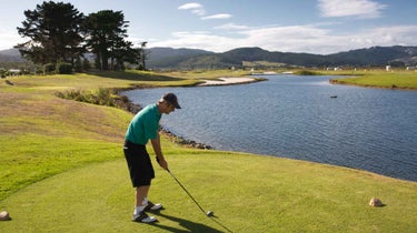 A golfer's tee shot over the water