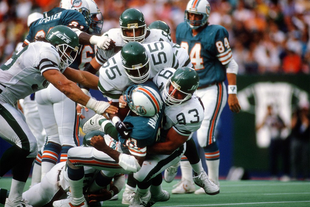 Marty Lyons helps teammate Alex Gordon make a tackle during the Jets' game against the Dolphins in 1989.