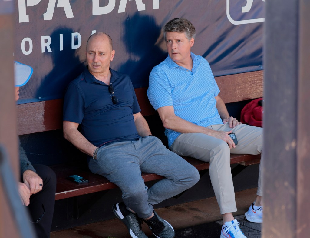 Yankees GM Brian Cashman (left) and owner Hal Steinbrenner sit in the dugout during spring training.