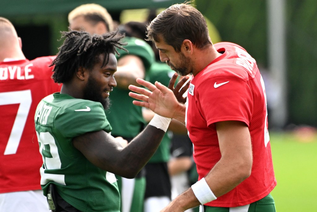 Aaron Rodgers and Michael Carter work on a handshake during the Jets' training camp practice.