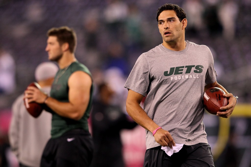 Mark Sanchez #6 (R) and Tim Tebow #15 of the New York Jets looks on as they warm up