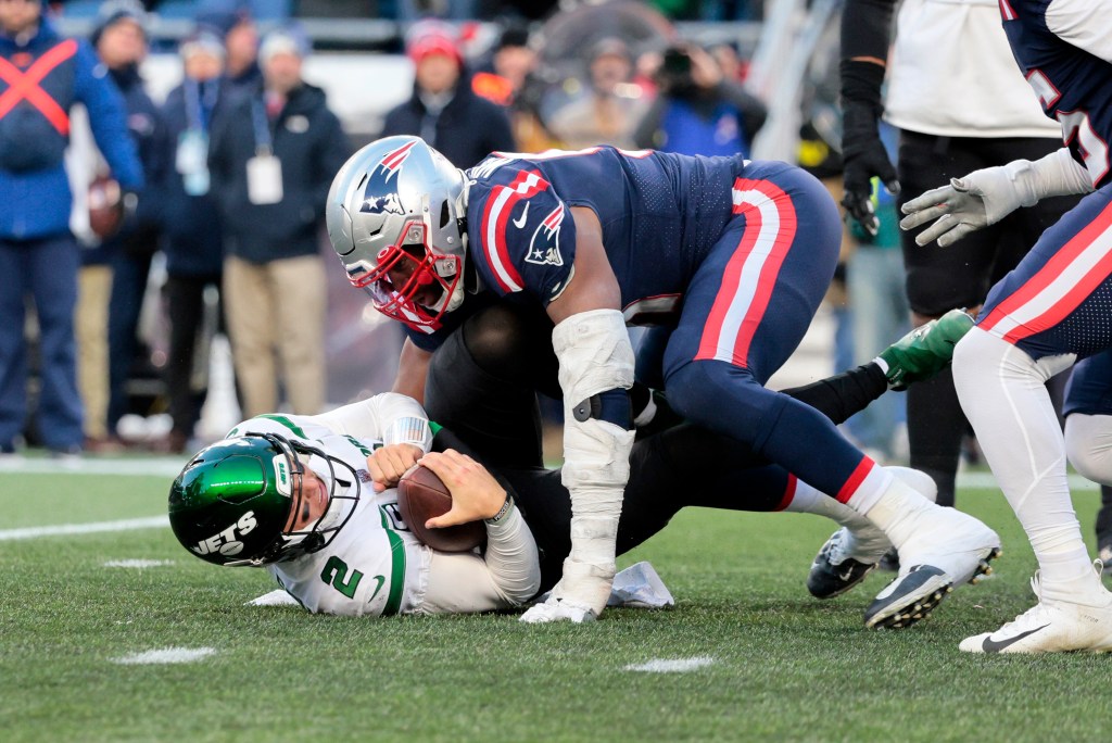 Zach Wilson cradles the ball on the turf during a Jets loss to the Patriots in 2022.