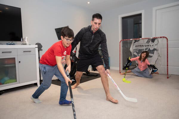 Chris Snow plays hockey inside with his children. 
