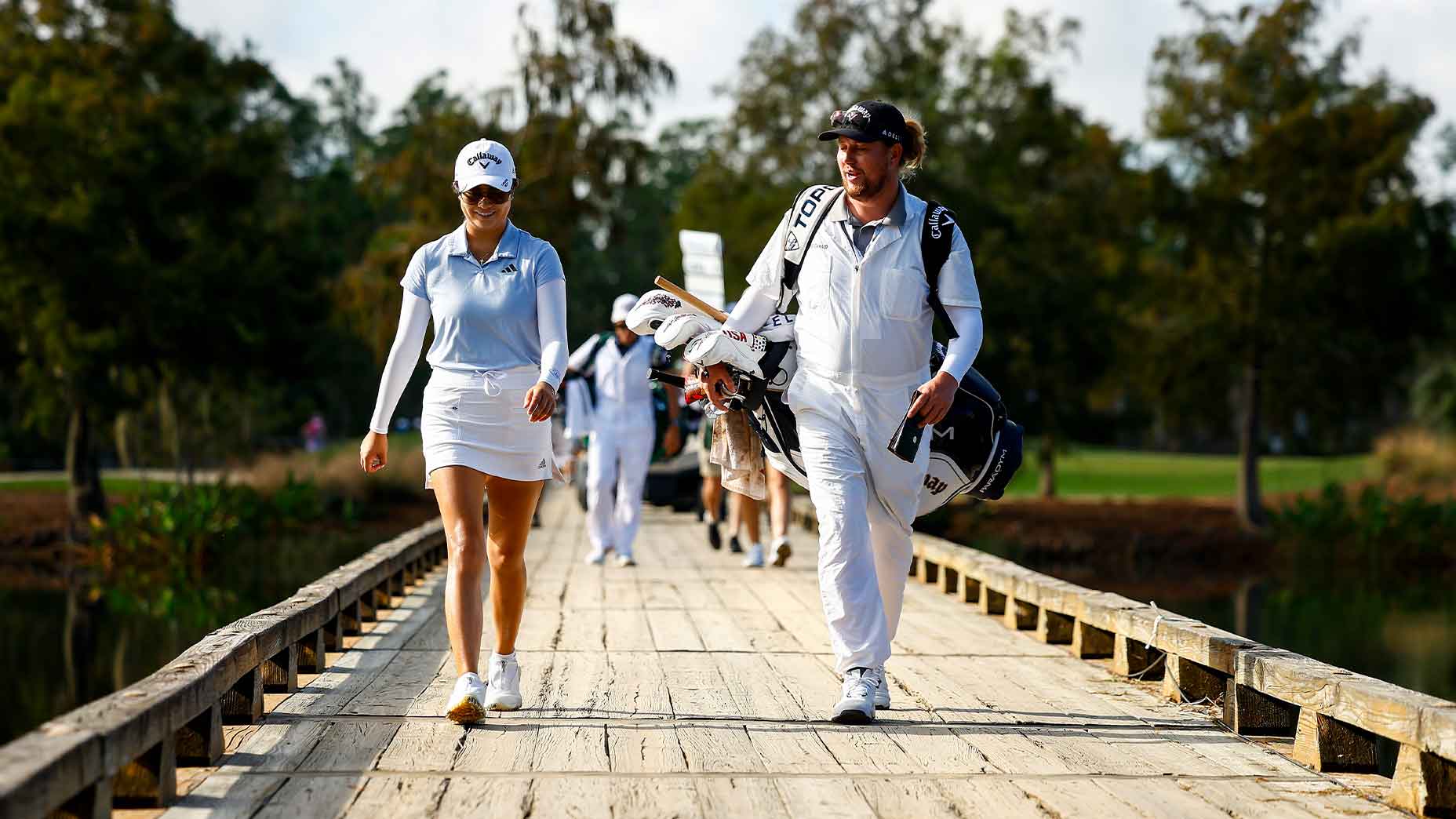rose zhang walks with her caddie over a bridge at the CME Tour Championship.
